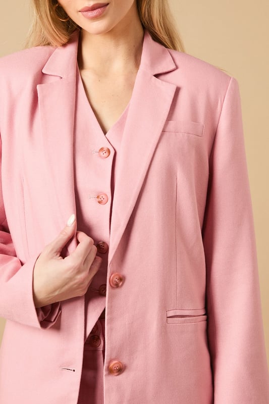 Oversized silhouette with relaxed shoulders for a contemporary, fashion-forward look
        Notched lapels and structured tailoring create a refined, elegant appearance
        Front button fastening with coordinating buttons for a cohesive finish
        Functional front pockets perfect for adding practicality to your formal ensemble
        Linen-look fabric offers a lightweight feel ideal for warmer weather occasions
    
    Make a statement with this beautifully crafted oversized blazer from Oasis. The relaxed fit creates a modern silhouette whilst maintaining a sophisticated edge that works brilliantly for both formal and casual settings. Style as seen with the matching wide-leg trousers for a coordinated suit that commands attention at summer weddings or garden parties. For everyday elegance, pair with slim-fit trousers and a simple camisole, finishing with delicate jewellery as shown on our model. The versatile nature of this blazer makes it perfect for layering during transitional seasons - wear open over a fitted dress for race day events or buttoned up with tailored shorts for a contemporary twist on occasion dressing. The clean lines and feminine cut embody Oasis' signature style whilst offering endless styling possibilities.
