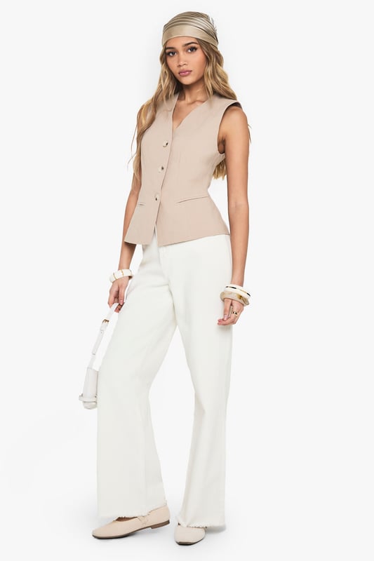 Sleeveless waistcoat with elegant V-neckline for a flattering silhouette
        Linen-look texture adds dimension and visual interest to your outfit
        Structured button-front design with subtle waist definition
        Versatile sleeveless cut perfect for layering or wearing alone
        Clean-lined silhouette with a contemporary tailored finish
    
    This sophisticated waistcoat brings effortless chic to your everyday wardrobe. The linen-look texture creates a relaxed yet refined aesthetic that works brilliantly for various casual occasions. Style with wide-leg trousers as shown for a coordinated ensemble that's perfect for family gatherings or weekend brunches. For cooler days, layer over a fitted long-sleeve top or under a lightweight jacket. Complete the look with a patterned headscarf and stacked bangles for a bohemian touch, or keep it minimal with delicate jewellery for a more understated approach. The neutral tone makes this waistcoat incredibly versatile - pair with denim for an elevated casual look or with tailored pieces for smart-casual events. Machine washable for easy care, this piece combines style with practicality for the fashion-forward woman.
