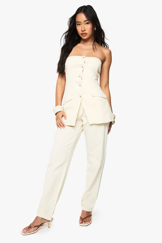 Chic bandeau-style vest with button-through front design
        Practical utility pockets at the hip for added functionality
        Structured silhouette that flatters the figure
        Crafted from breathable cotton fabric for all-day comfort
        Versatile regular fit that works beautifully as both a standalone piece or layered item
    
    This sophisticated bandeau vest offers effortless style for the fashion-forward woman. The clean lines and strapless design create a contemporary silhouette that's perfect for warmer days. Style with the matching wide-leg trousers as seen on our model for a coordinated summer ensemble, or pair with your favourite denim for a more casual approach. The cotton fabric ensures breathability whilst maintaining structure, making it ideal for family gatherings or weekend brunches. For evening occasions, layer with a lightweight blazer and accessorise with statement jewellery. This Boohoo piece transitions seamlessly from daytime casual with trainers to evening drinks when styled with strappy sandals, offering remarkable versatility for your wardrobe.