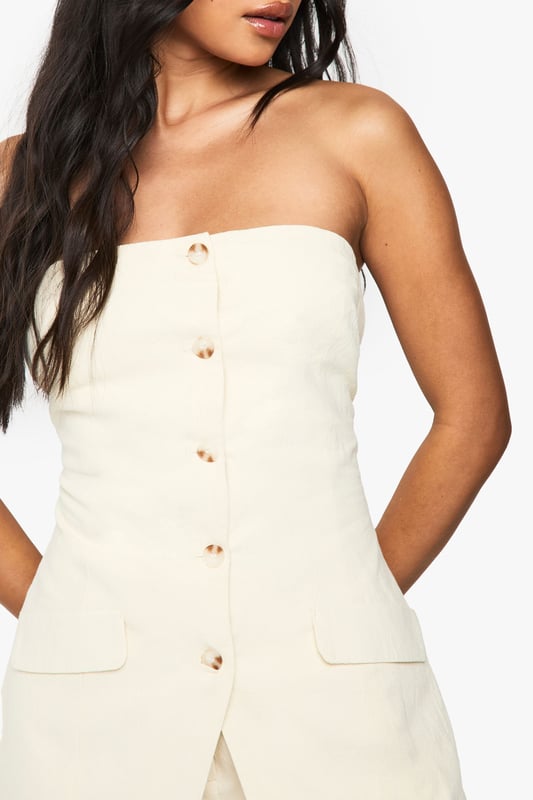 Chic bandeau-style vest with button-through front design
        Practical utility pockets at the hip for added functionality
        Structured silhouette that flatters the figure
        Crafted from breathable cotton fabric for all-day comfort
        Versatile regular fit that works beautifully as both a standalone piece or layered item
    
    This sophisticated bandeau vest offers effortless style for the fashion-forward woman. The clean lines and strapless design create a contemporary silhouette that's perfect for warmer days. Style with the matching wide-leg trousers as seen on our model for a coordinated summer ensemble, or pair with your favourite denim for a more casual approach. The cotton fabric ensures breathability whilst maintaining structure, making it ideal for family gatherings or weekend brunches. For evening occasions, layer with a lightweight blazer and accessorise with statement jewellery. This Boohoo piece transitions seamlessly from daytime casual with trainers to evening drinks when styled with strappy sandals, offering remarkable versatility for your wardrobe.