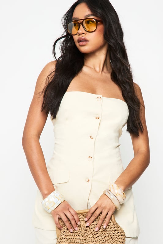 Chic bandeau-style vest with button-through front design
        Practical utility pockets at the hip for added functionality
        Structured silhouette that flatters the figure
        Crafted from breathable cotton fabric for all-day comfort
        Versatile regular fit that works beautifully as both a standalone piece or layered item
    
    This sophisticated bandeau vest offers effortless style for the fashion-forward woman. The clean lines and strapless design create a contemporary silhouette that's perfect for warmer days. Style with the matching wide-leg trousers as seen on our model for a coordinated summer ensemble, or pair with your favourite denim for a more casual approach. The cotton fabric ensures breathability whilst maintaining structure, making it ideal for family gatherings or weekend brunches. For evening occasions, layer with a lightweight blazer and accessorise with statement jewellery. This Boohoo piece transitions seamlessly from daytime casual with trainers to evening drinks when styled with strappy sandals, offering remarkable versatility for your wardrobe.