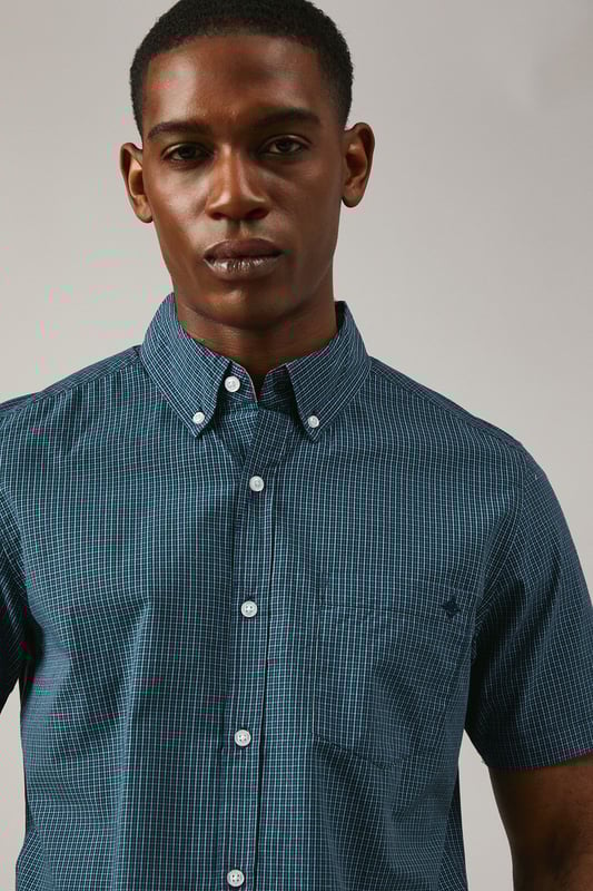 Classic button-down collar with traditional gingham check pattern
        Short sleeves with neat hem for warm-weather comfort
        Chest pocket detail adds functional style
        Back yoke with centre pleat for enhanced movement
        Regular fit silhouette suitable for various body types
    
    This Maine gingham check shirt combines timeless British style with everyday versatility. The woven fabric offers a structured yet comfortable feel, perfect for casual occasions that call for a touch of refinement. Style it as shown with dark denim jeans and white trainers for a relaxed weekend look, or pair with chino shorts and loafers for summer garden parties. The button-down collar maintains a neat appearance throughout the day, while the short sleeves make it ideal for family gatherings and casual outings during warmer months. This shirt transitions effortlessly from daytime casual to evening drinks, making it a wardrobe essential that works across multiple seasons. Layer under a lightweight jumper when temperatures drop or wear open over a plain t-shirt for a more contemporary approach to casual dressing.