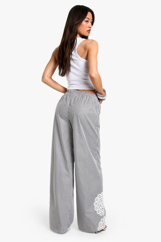 Wide leg trousers featuring delicate floral embroidery detailing at the hem
        Comfortable elasticated waistband with adjustable drawstring tie
        Classic pinstripe pattern throughout for a subtle textured look
        Relaxed, flowing silhouette perfect for taller frames
        Woven fabric that drapes beautifully for effortless movement
    
    These striking wide leg trousers combine casual comfort with distinctive style. The standout floral embroidery at the hem creates a beautiful focal point, while the pinstripe pattern adds a touch of sophistication to your everyday wardrobe. Style with a simple crop top as shown for a balanced silhouette that showcases the dramatic wide leg cut. These trousers are perfect for casual gatherings where you want to make an impression without sacrificing comfort. Pair with flat sandals and a small handbag for daytime events, or dress them up with wedges and statement jewellery for evening occasions. The relaxed fit makes these trousers ideal for family gatherings, brunches with friends, or stylish yet comfortable travel attire. Their versatility allows for countless styling options throughout the seasons.