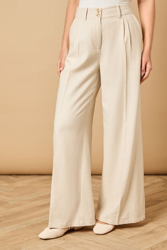 Tailored wide leg design with elegant front pleats for a flattering silhouette
        High-rise waistband with button fastening for a secure and comfortable fit
        Practical side pockets perfect for everyday essentials
        Flowing wide leg cut creates a graceful drape when walking
        Versatile woven fabric suitable for both formal occasions and smart-casual styling
    
    These sophisticated wide leg trousers from Oasis present the perfect balance of comfort and elegance. The tailored design features a flattering high waist that creates a sleek silhouette, whilst the generous wide leg cut offers a contemporary twist on classic formal wear. Style with the coordinating waistcoat for a chic two-piece ensemble perfect for summer weddings and race day events. For more relaxed occasions, pair with a simple silk camisole and metallic sandals as shown. The clean lines and structured fabric make these trousers an excellent choice for important meetings or graduation ceremonies, whilst their lightweight feel ensures you'll remain comfortable throughout the day. Add statement jewellery and a clutch bag to transform them into an evening-ready outfit that radiates refined femininity.