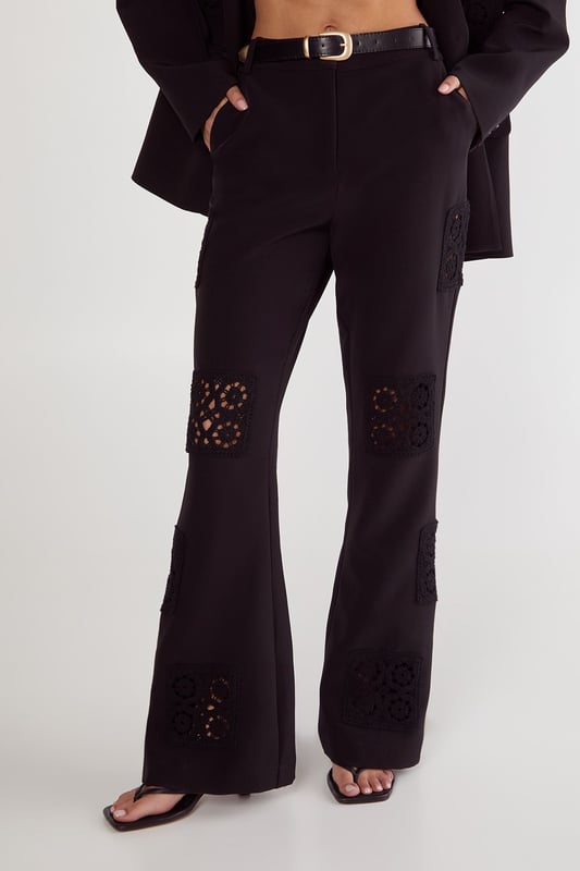 Tailored trousers featuring intricate crochet inserts at the knees for a distinctive design element
        Flattering flared silhouette that gracefully widens from the knee to create an elongated leg line
        High-rise waistband with belt loops, perfect for styling with statement belts
        Sleek side pockets for practical functionality without compromising on style
        Versatile design that transitions seamlessly from daytime sophistication to evening elegance
    
    These Nasty Gal tailored trousers redefine smart dressing with their artful crochet inserts that add textural interest to a classic silhouette. The flared leg creates a balanced proportion that flatters all figures, whilst the high-rise fit accentuates the waist beautifully. Style them as seen with an oversized blazer and minimal top for a contemporary take on tailoring, or pair with a crisp button-down shirt for more formal settings. The trousers work brilliantly for sophisticated events where you want to make an impression without appearing overdressed. For evening occasions, team with a silk camisole and strappy heels, or dress down for smart-casual gatherings with a fitted turtleneck and elegant flats. The crochet detail ensures these trousers stand out from standard tailoring, making them a versatile investment piece for your wardrobe.