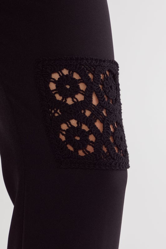 Tailored trousers featuring intricate crochet inserts at the knees for a distinctive design element
        Flattering flared silhouette that gracefully widens from the knee to create an elongated leg line
        High-rise waistband with belt loops, perfect for styling with statement belts
        Sleek side pockets for practical functionality without compromising on style
        Versatile design that transitions seamlessly from daytime sophistication to evening elegance
    
    These Nasty Gal tailored trousers redefine smart dressing with their artful crochet inserts that add textural interest to a classic silhouette. The flared leg creates a balanced proportion that flatters all figures, whilst the high-rise fit accentuates the waist beautifully. Style them as seen with an oversized blazer and minimal top for a contemporary take on tailoring, or pair with a crisp button-down shirt for more formal settings. The trousers work brilliantly for sophisticated events where you want to make an impression without appearing overdressed. For evening occasions, team with a silk camisole and strappy heels, or dress down for smart-casual gatherings with a fitted turtleneck and elegant flats. The crochet detail ensures these trousers stand out from standard tailoring, making them a versatile investment piece for your wardrobe.