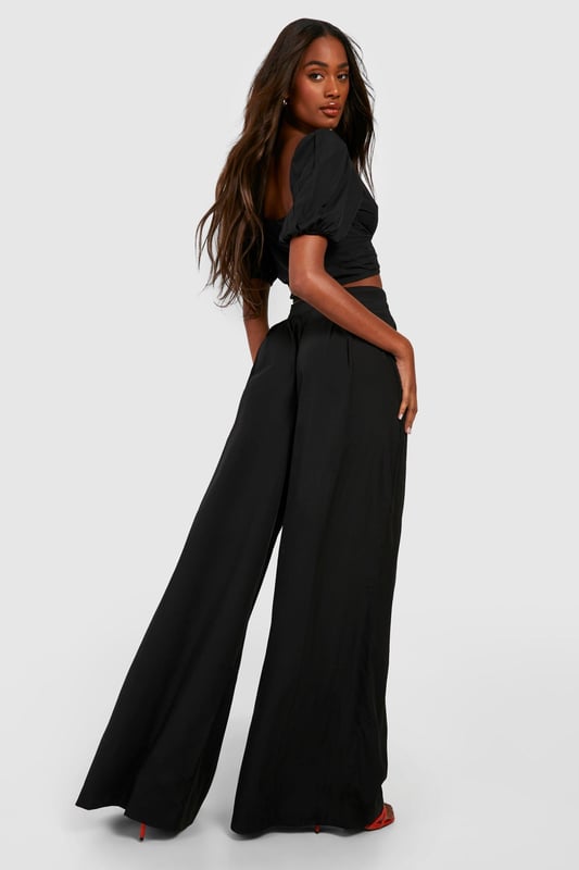 Wide leg palazzo design for a dramatic silhouette
        Pleated front detail adds texture and sophistication
        High-waisted fit elongates the legs
        Woven crepe fabric offers a luxurious drape
        Versatile style suitable for various casual occasions
    
    Make a statement with these eye-catching pleat front wide leg palazzo trousers. The dramatic silhouette created by the wide leg design is perfect for those who want to stand out from the crowd. The high-waisted fit not only accentuates your curves but also creates the illusion of longer legs. Pair these trousers with a cropped top, as shown in the image, for a trendy and balanced look. The woven crepe fabric ensures a beautiful drape that moves gracefully with every step. These trousers are ideal for casual events or family gatherings where you want to look effortlessly chic. For a laid-back daytime look, team them with trainers and a simple tee. When the evening calls for something more refined, swap the trainers for heeled sandals and add some statement jewellery to elevate your ensemble. The versatility of these trousers makes them a must-have addition to any fashion-forward wardrobe.
