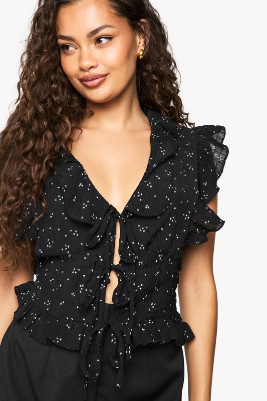 Flirty V-neckline with charming front tie detail for adjustable styling
        Feminine ruffle sleeves adding playful movement and dimension
        Delicate all-over floral print creating visual interest
        Loose fit design offering comfortable, relaxed silhouette
        Cropped length perfect for high-waisted bottoms
    
    This enchanting ruffle blouse from Boohoo brings carefree charm to your everyday wardrobe. The loose-fitting silhouette creates an effortlessly chic look whilst the front tie detail allows you to customise your neckline depth. Style with your favourite denim shorts and trainers for daytime outings, or pair with a fitted mini skirt as seen on our model for casual gatherings. The ruffle sleeve detailing adds a touch of femininity that works beautifully for family brunches or weekend coffee dates. For cooler evenings, layer under a lightweight denim jacket and finish with simple hoop earrings. The versatile design makes this blouse a true wardrobe hero that transitions seamlessly from casual park days to relaxed evening drinks with friends.