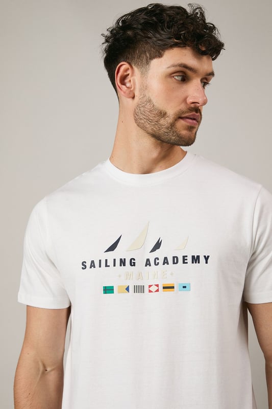 Classic crew neck t-shirt from Maine's Sailing Academy collection
        Soft cotton jersey fabric for all-day comfort
        Distinctive nautical graphic with sailing flags design
        Clean, minimalist back design for versatile styling
        Regular fit silhouette suitable for various body types
    
    This Maine Sailing Academy t-shirt combines casual comfort with maritime charm. The standout graphic featuring nautical flags brings a touch of seafaring style to your everyday wardrobe. As shown, it pairs perfectly with dark shorts and white trainers for a relaxed weekend look. The versatile design makes it ideal for coastal holidays, summer barbecues, or casual meet-ups with mates. Layer under a navy bomber jacket when the temperature drops or team with chinos and boat shoes for a smarter nautical-inspired ensemble. The clean-cut silhouette and breathable cotton fabric ensure you'll stay comfortable whether you're strolling along the harbour or enjoying a casual lunch at your local pub. A wardrobe essential that transitions effortlessly from daytime outings to laid-back evening gatherings.