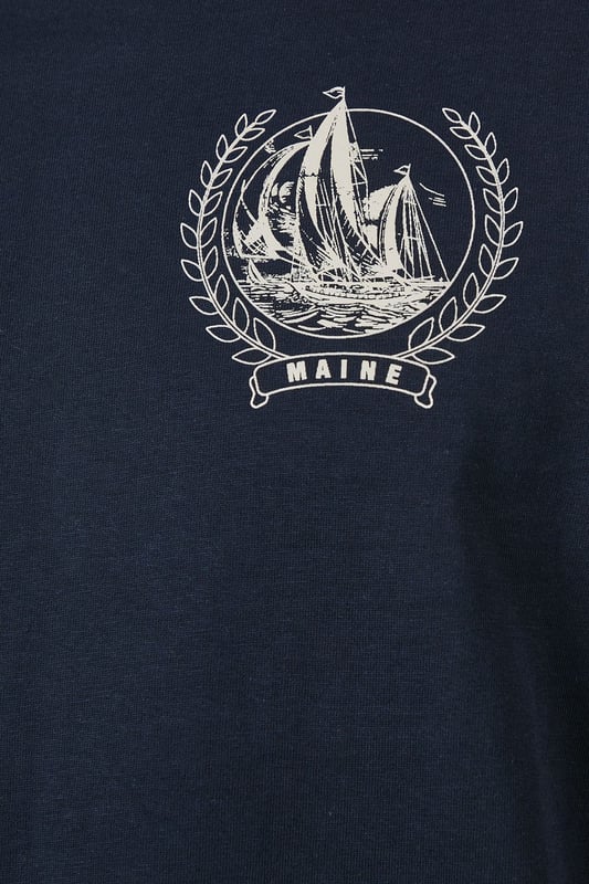 Soft jersey fabric for all-day comfort and breathability
        Classic crew neckline with ribbed trim for a neat finish
        Distinctive coastal ship emblem on chest for nautical appeal
        Short sleeves with clean-cut edges for a streamlined look
        Relaxed fit through the body offering ease of movement
    
    This Maine coastal print t-shirt brings maritime charm to your casual wardrobe. The understated design features a distinctive sailing ship emblem encircled by a laurel wreath, creating a subtle focal point against the navy background. Style it as shown with light-coloured shorts and white trainers for a fresh summer look perfect for beachside strolls or weekend brunches. For cooler evenings, layer under an unstructured blazer or light cotton overshirt. The versatile design transitions effortlessly from daytime casual to relaxed evening gatherings. The cotton jersey construction ensures this t-shirt remains comfortable throughout the day, making it an ideal choice for family outings, casual meet-ups with friends, or simply lounging at home with understated style.