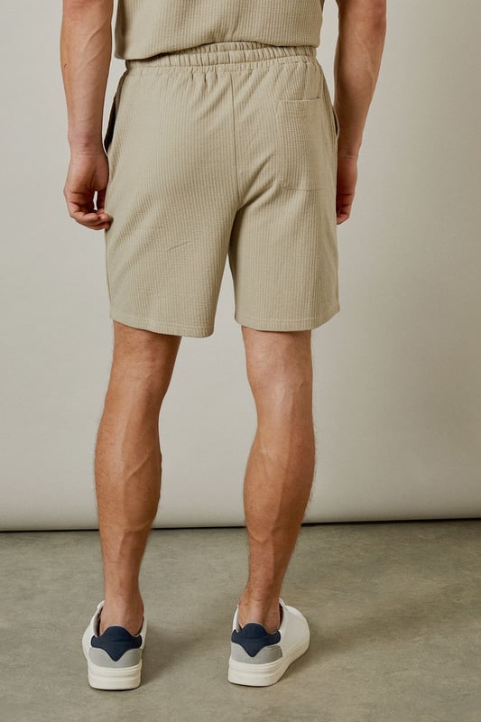 Distinctive seersucker texture adds visual interest and breathability to these casual shorts
        Comfortable elasticated waistband with adjustable drawstring for a personalised fit
        Relaxed leg shape offers ease of movement for all-day comfort
        Mid-thigh length provides a modern silhouette that works for various body types
        Cotton-rich fabric ensures these shorts remain soft and comfortable throughout the day
    
    These Burton seersucker shorts combine classic style with modern comfort, perfect for the man who appreciates timeless fashion. The textured fabric adds subtle sophistication while remaining thoroughly practical for warm-weather wear. Style them as shown with a matching polo shirt for a coordinated look that works brilliantly for weekend barbecues or casual pub gatherings with mates. Alternatively, pair with a crisp white t-shirt and trainers for an effortless daytime ensemble. The neutral tone makes these shorts incredibly versatile, allowing them to complement your existing wardrobe with ease. They're ideal for family gatherings, sporting events, or simply relaxing in the garden on sunny afternoons. Machine washable at 30 degrees, these shorts offer both style and practicality for the modern British man.