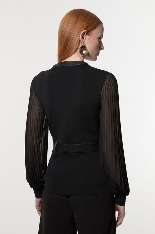 This Karen Millen top seamlessly blends sophistication with contemporary style. The knitted body offers a sleek fit, while the pleated woven sleeves add a touch of drama and movement. The faux leather trim along the V-neckline and waistband creates a striking contrast, enhancing the overall silhouette. Perfect for both day and evening wear, this top can be styled with tailored trousers and heels for a formal event, or paired with a pencil skirt for an office look. The versatility of this piece allows for endless styling possibilities, making it a valuable addition to any wardrobe. Whether you're attending a wedding, a cocktail party, or a business meeting, this top will ensure you look polished and fashion-forward.  Elegant V-neck design with faux leather trim Pleated woven sleeves for added texture Knitted body with a fitted silhouette Faux leather waistband for a defined shape Versatile piece suitable for various occasions