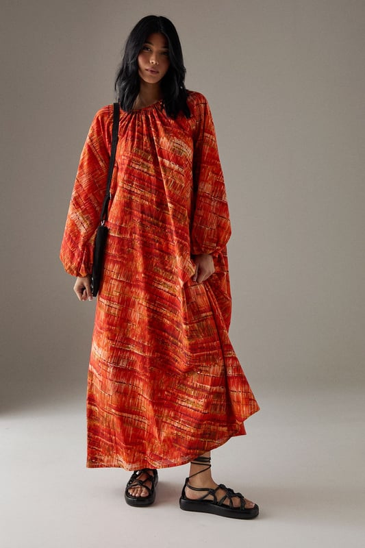 Striking trapeze silhouette creating a flowing, relaxed fit that drapes beautifully from shoulder to hem
        Voluminous balloon sleeves with gathered cuffs for a dramatic yet comfortable statement
        Round neckline with delicate gathering detail adding subtle texture and dimension
        Midi length design perfect for versatile styling across seasons
        100% cotton fabric offering breathable comfort for all-day wear
    
    This Cotton Trapeze Smock Midi Dress from Warehouse conveys effortless confidence with its bold pattern and relaxed silhouette. The generous cut creates a flattering shape that moves gracefully with your body, while the gathered neckline adds a touch of feminine detail. Style with chunky flat sandals as seen on our model for casual daytime outings, or pair with trainers and a crossbody bag for weekend market trips. For cooler weather, layer over a thin rollneck and add ankle boots for dimension. This versatile piece transitions seamlessly from family lunches to gallery visits - simply customise with your favourite jewellery to reflect your personal style. The breathable cotton construction ensures comfort throughout the day, making this dress a reliable choice for lengthy shopping excursions or informal garden gatherings.
