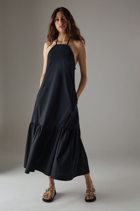 Crafted from breathable cotton poplin fabric for all-day comfort
        Delicate crochet trim detailing along the halterneck neckline adds a feminine touch
        Flattering drop waist silhouette with a relaxed midi length
        Elegant tiered hem creates movement and dimension
        Thin halter straps with back fastening for an adjustable fit
    
    This Warehouse sundress combines effortless style with practical comfort for warm-weather dressing. The relaxed drop waist silhouette creates a carefree aesthetic while the crochet trim adds a touch of artisanal detail to the halterneck design. Style with flat sandals and a woven tote for farmers' markets and weekend brunches, or dress up with espadrille wedges and statement earrings for garden parties. The versatile midi length works beautifully for coastal holidays - simply throw over your swimwear with a wide-brimmed hat for beach-to-bar ease. For cooler evenings, layer with a lightweight denim jacket and switch to ankle boots for an extended seasonal wardrobe staple that transitions seamlessly from day to night.