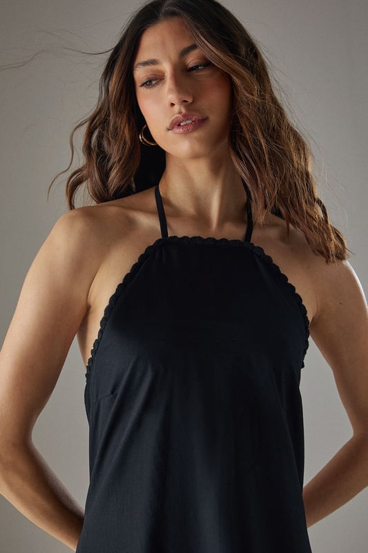 Crafted from breathable cotton poplin fabric for all-day comfort
        Delicate crochet trim detailing along the halterneck neckline adds a feminine touch
        Flattering drop waist silhouette with a relaxed midi length
        Elegant tiered hem creates movement and dimension
        Thin halter straps with back fastening for an adjustable fit
    
    This Warehouse sundress combines effortless style with practical comfort for warm-weather dressing. The relaxed drop waist silhouette creates a carefree aesthetic while the crochet trim adds a touch of artisanal detail to the halterneck design. Style with flat sandals and a woven tote for farmers' markets and weekend brunches, or dress up with espadrille wedges and statement earrings for garden parties. The versatile midi length works beautifully for coastal holidays - simply throw over your swimwear with a wide-brimmed hat for beach-to-bar ease. For cooler evenings, layer with a lightweight denim jacket and switch to ankle boots for an extended seasonal wardrobe staple that transitions seamlessly from day to night.