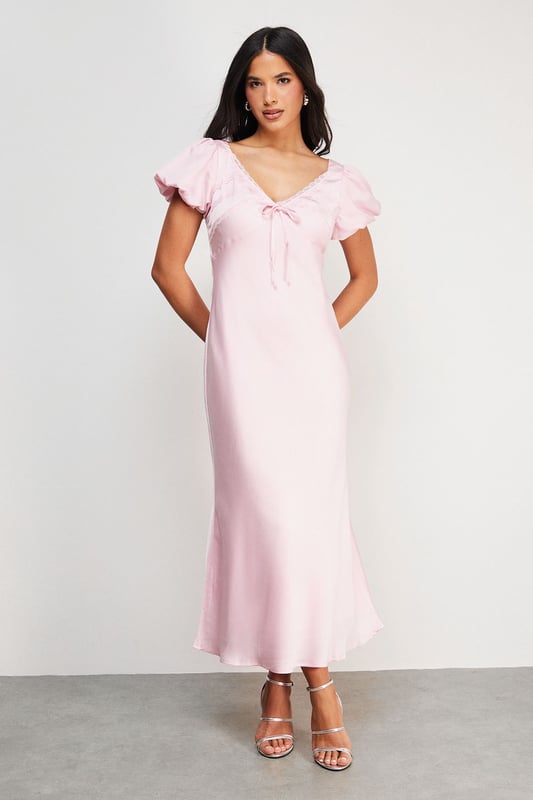 Elegant satin midi tea dress with delicate lace insert detailing
        Feminine puff sleeves with subtle volume for a romantic silhouette
        Flattering V-neckline with charming bow tie detail
        Flowing midi length design that falls gracefully to mid-calf
        Fully lined for comfort and a smooth, refined drape
    
    This enchanting Warehouse tea dress combines vintage-inspired charm with contemporary styling. The satin fabric creates a lustrous finish that catches the light beautifully, whilst the puff sleeves and lace inserts add a touch of feminine flair. Style with strappy metallic sandals as seen on our model for daytime gatherings, or dress down with white trainers and a denim jacket for weekend brunches. The versatile midi length works wonderfully for family celebrations or garden parties-simply add delicate jewellery and a woven clutch to complete the look. For cooler days, layer with a lightweight cardigan and ankle boots for an effortlessly chic ensemble that transitions seamlessly from day to evening. This dress embodies confident femininity with its subtle details and timeless silhouette.