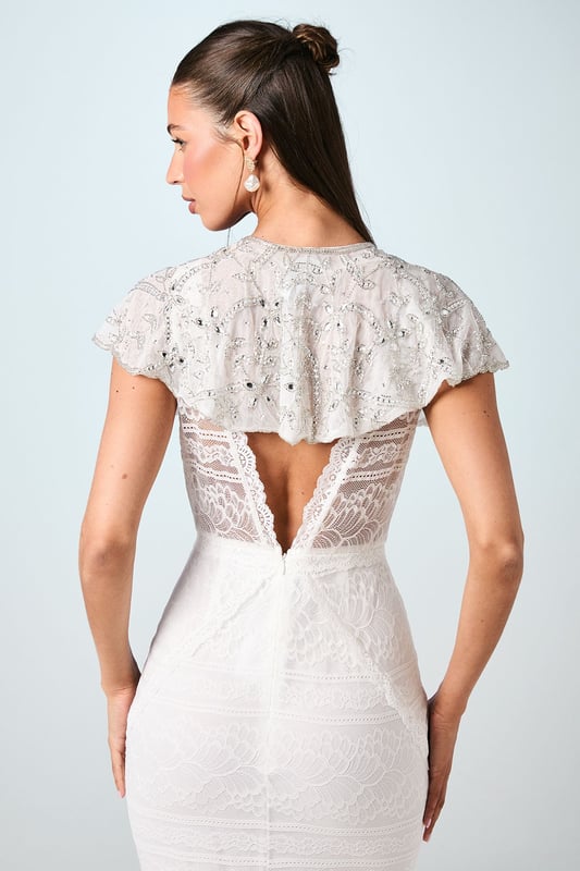 Exquisite hand-stitched cape adorned with sparkling gem embellishments and delicate sequin detailing
        Elegant flutter cap sleeves create a graceful silhouette that frames the shoulders beautifully
        Stunning open back design with sheer panels adds a contemporary touch to this traditional bridal accessory
        Intricate beadwork catches the light with every movement for a truly magical effect
        Versatile piece that can be styled with various wedding gown silhouettes for a personalised bridal look
    
    Make a breathtaking entrance on your special day with this enchanting bridal cape from Coast. The delicate hand-stitched detailing and carefully placed gem embellishments create a halo of radiance around your shoulders, adding a touch of glamour to your wedding ensemble. The thoughtfully designed open back ensures your gown remains the centrepiece whilst the cape adds dimension and visual interest. Style with a sleek updo and drop earrings as seen on our model to showcase the intricate neckline, or wear with flowing locks for a more romantic aesthetic. Perfect for the ceremony and photographs, this cape transitions beautifully from the aisle to the reception, offering a sophisticated layer that can be removed later to reveal a second look for evening celebrations. A truly special accessory that will become a cherished keepsake of your wedding day.