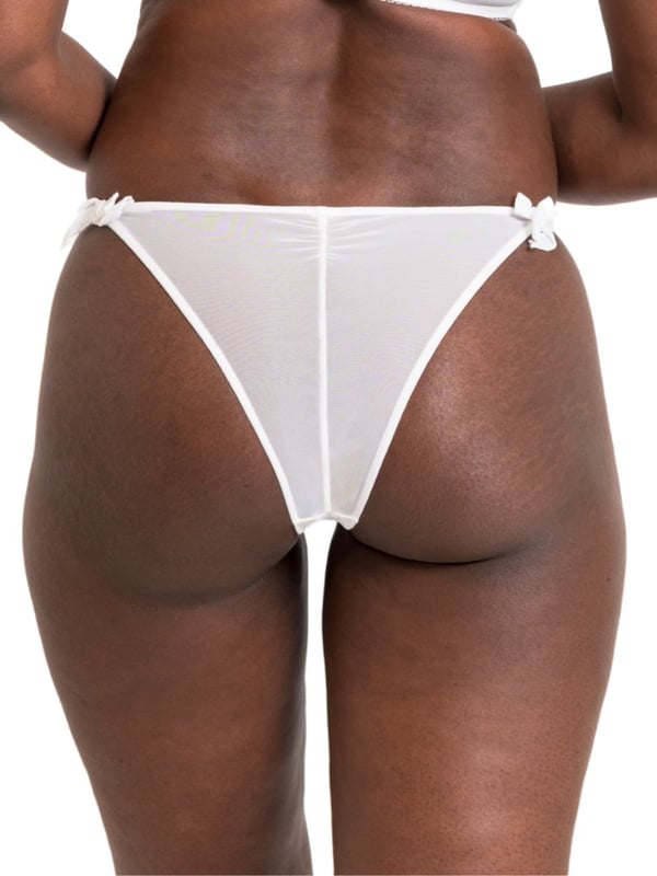 Curvy Kate Flora Tanga. Low rise tanga brief with broderie anglaise inspired embroidered fabric, cotton trims, scalloped edging, bow detailing and a seamless mesh back. The product is recommended for hand wash only.