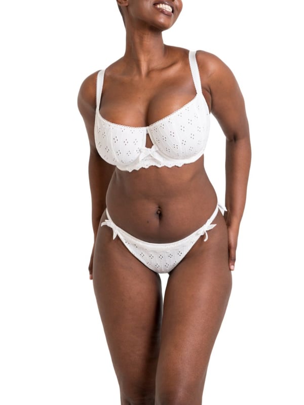 Curvy Kate Flora Tanga. Low rise tanga brief with broderie anglaise inspired embroidered fabric, cotton trims, scalloped edging, bow detailing and a seamless mesh back. The product is recommended for hand wash only.
