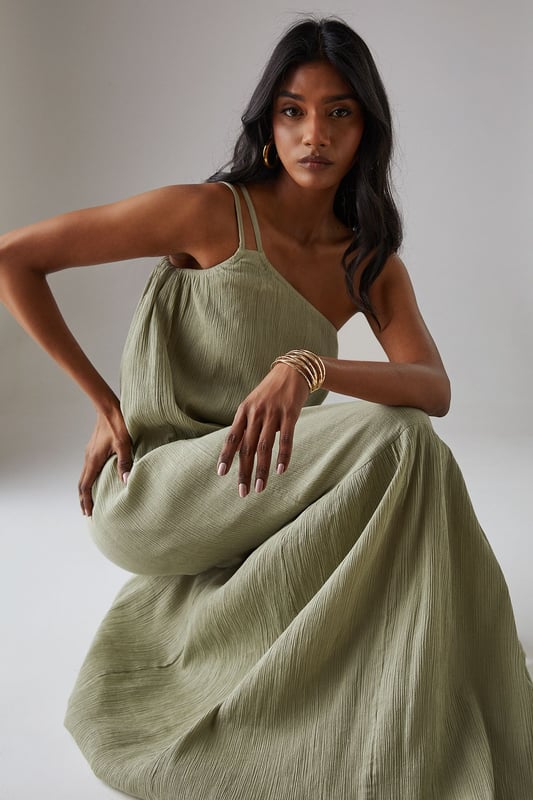 Asymmetric one-shoulder design with elegant double strap detail
        Lightweight cheesecloth fabric creates a breezy, effortless drape
        Flowing maxi length with feminine tiered hem detail
        Relaxed silhouette offers comfortable movement for all-day wear
        Versatile sundress that transitions seamlessly from day to evening occasions
    
    This striking Warehouse maxi sundress commands attention with its distinctive asymmetric neckline and double strap detail. The lightweight cheesecloth fabric creates a beautifully fluid silhouette that moves gracefully with every step, while the tiered hem adds a touch of feminine flair. For formal occasions, style with metallic strappy heels and statement gold jewellery as seen on our model - the chunky bangle creates a perfect contrast against the dress's soft texture. Alternatively, embrace a more relaxed daytime look with leather sandals and a woven clutch. The versatile design makes it an ideal choice for summer weddings, garden parties, or sophisticated evening events where you wish to project confidence with an edgy yet feminine aesthetic. The one-shoulder design offers a contemporary twist on classic occasion wear, ensuring you stand out for all the right reasons.