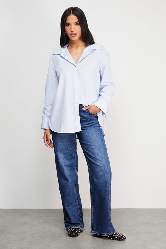 Oversized fit with classic collar and button-through front for a relaxed silhouette
        Distinctive bow-tie back detail creates a feminine twist on the traditional shirt
        Long sleeves with button cuffs offer versatility for year-round styling
        Cotton fabric provides breathable comfort for all-day wear
        Subtle split back design adds movement and contemporary flair
    
    This Warehouse oversized shirt reinvents the classic button-down with its striking bow-back detail. The relaxed fit creates an effortlessly chic look that works beautifully with straight-leg jeans and flats for casual outings. For a more polished ensemble, try half-tucking the front into high-waisted trousers and adding a structured tote. The cotton construction ensures comfort whilst maintaining a crisp appearance throughout the day. Perfect for family gatherings or weekend brunches, this versatile piece transitions seamlessly from daytime casual to evening drinks when paired with statement earrings and ankle boots. The thoughtful back detail adds interest when layered under jumpers or jackets, making this shirt a standout addition to your wardrobe that works across multiple seasons.