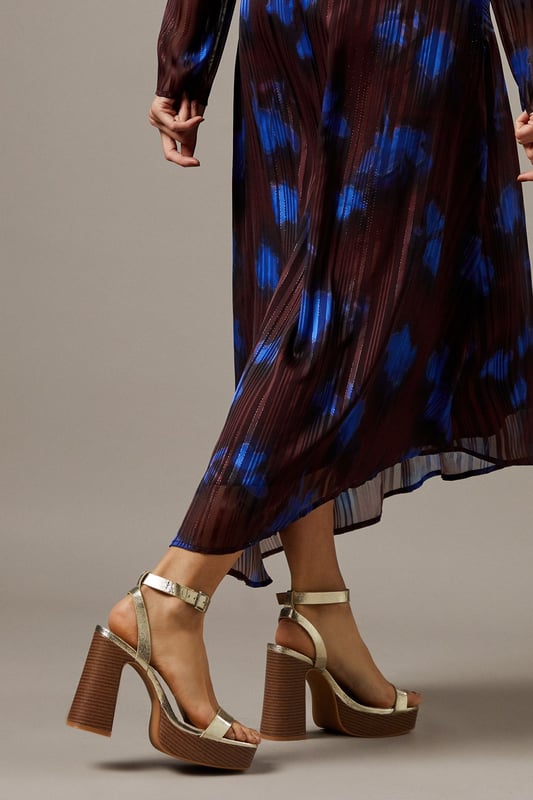 Striking metallic faux leather finish that catches the light beautifully
        Chunky wooden-effect platform for added height and stability
        Elegant high block heel measuring between 7-9cm
        Secure ankle strap with adjustable buckle fastening
        Open toe design perfect for showcasing your favourite pedicure
    
    These Faith Ebony platform sandals combine retro-inspired design with contemporary flair. The metallic finish adds a touch of glamour to any outfit, while the substantial platform and block heel provide comfort without sacrificing style. Pair with flowing midi dresses for garden parties, or team with cropped jeans and an oversized shirt for casual weekend brunches. The ankle strap ensures security while walking, making these an ideal choice for all-day wear despite their impressive height. The versatile design transitions effortlessly from daytime family gatherings to evening drinks with friends. The contrast between the sleek upper and textured wooden-effect heel creates visual interest that will complement both casual and smart-casual ensembles in your wardrobe.
