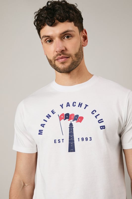 Classic crew neck t-shirt featuring the distinctive Maine Yacht Club graphic print
        Short sleeves with neat ribbed trim for a clean finish
        Soft jersey fabric offering comfort for all-day wear
        Vintage-inspired nautical design with established date detail
        Relaxed fit that's perfect for casual styling
    
    This Maine Yacht Club t-shirt combines timeless nautical charm with everyday wearability. The distinctive graphic print adds character to your casual collection, whilst the comfortable jersey fabric ensures it remains a go-to piece for relaxed days. Style as seen with dark shorts and white trainers for a classic summer look that works brilliantly for weekend brunches or coastal walks. For cooler evenings, layer under a lightweight bomber jacket or denim shirt. This versatile t-shirt transitions effortlessly from daytime casual to evening gatherings with friends - simply swap the shorts for chinos and add a casual blazer to create a smart-casual ensemble that maintains its laid-back appeal. Perfect for holidays, festivals or simply enjoying the British summer.