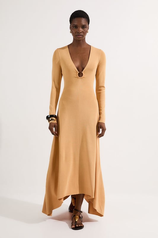 Make a statement at your next formal occasion with this captivating Karen Millen slinky knitted dress. The deep V neckline adorned with the signature hardware keyring detail creates a focal point that draws the eye, whilst the fluid knitted fabric drapes beautifully over your curves. Style with strappy metallic heels and a structured clutch for evening events, or dress down with embellished flat sandals for sophisticated daytime gatherings. The versatile design transitions seamlessly from wedding guest attire to race day ensemble, with the long sleeves offering coverage for cooler evening affairs. Add statement earrings and a sleek updo to showcase the elegant neckline, completing a look that commands attention whilst maintaining refined sophistication.  Striking V neckline with distinctive hardware keyring detail for a contemporary edge Elegant long sleeves with contrasting metallic accent detailing at the cuffs Flattering slinky knitted fabric that gracefully contours the silhouette Sophisticated maxi length with a subtle asymmetric hemline Figure-enhancing fit that creates a refined feminine profile