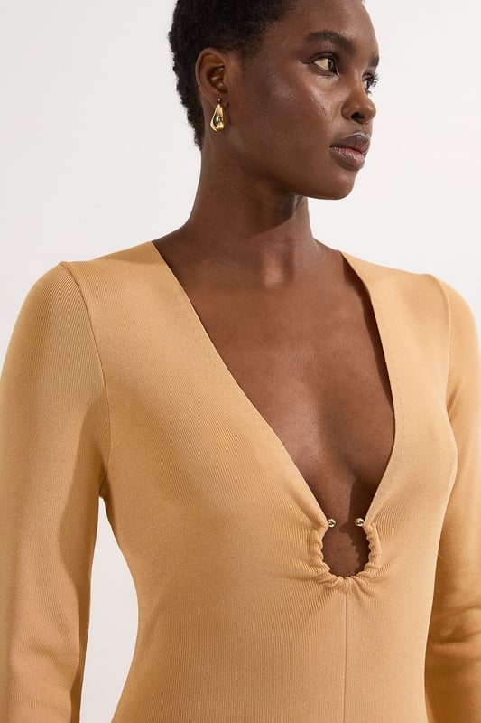 Make a statement at your next formal occasion with this captivating Karen Millen slinky knitted dress. The deep V neckline adorned with the signature hardware keyring detail creates a focal point that draws the eye, whilst the fluid knitted fabric drapes beautifully over your curves. Style with strappy metallic heels and a structured clutch for evening events, or dress down with embellished flat sandals for sophisticated daytime gatherings. The versatile design transitions seamlessly from wedding guest attire to race day ensemble, with the long sleeves offering coverage for cooler evening affairs. Add statement earrings and a sleek updo to showcase the elegant neckline, completing a look that commands attention whilst maintaining refined sophistication.  Striking V neckline with distinctive hardware keyring detail for a contemporary edge Elegant long sleeves with contrasting metallic accent detailing at the cuffs Flattering slinky knitted fabric that gracefully contours the silhouette Sophisticated maxi length with a subtle asymmetric hemline Figure-enhancing fit that creates a refined feminine profile