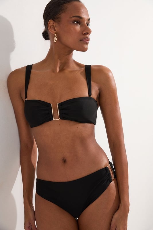 These sophisticated Karen Millen bikini bottoms bring a touch of luxury to your beachwear collection. The striking gold trim adds a refined accent that catches the light beautifully as you lounge poolside or stroll along the shore. Pair with the coordinating bandeau top for a cohesive look that's perfect for your summer getaway. Style with oversized sunglasses and a flowing kaftan for elegant poolside glamour, or team with a linen shirt and sandals when heading to a beachside lunch. These bottoms offer the perfect balance of comfort and sophistication for your next sun-soaked holiday.   Distinctive gold-tone trim detail on the side Mid-rise design offering comfortable coverage and a flattering silhouette Soft, stretchy fabric Sleek, minimalist design that pairs beautifully with the matching bandeau top  Matching piece sold separately.