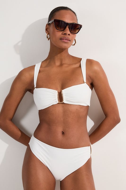 These sophisticated Karen Millen bikini bottoms bring a touch of luxury to your beachwear collection. The striking gold trim adds a refined accent that catches the light beautifully as you lounge poolside or stroll along the shore. Pair with the coordinating bandeau top for a cohesive look that's perfect for your summer getaway. Style with oversized sunglasses and a flowing kaftan for elegant poolside glamour, or team with a linen shirt and sandals when heading to a beachside lunch. These bottoms offer the perfect balance of comfort and sophistication for your next sun-soaked holiday.   Distinctive gold-tone trim detail on the side Mid-rise design offering comfortable coverage and a flattering silhouette Soft, stretchy fabric Sleek, minimalist design that pairs beautifully with the matching bandeau top  Matching piece sold separately.
