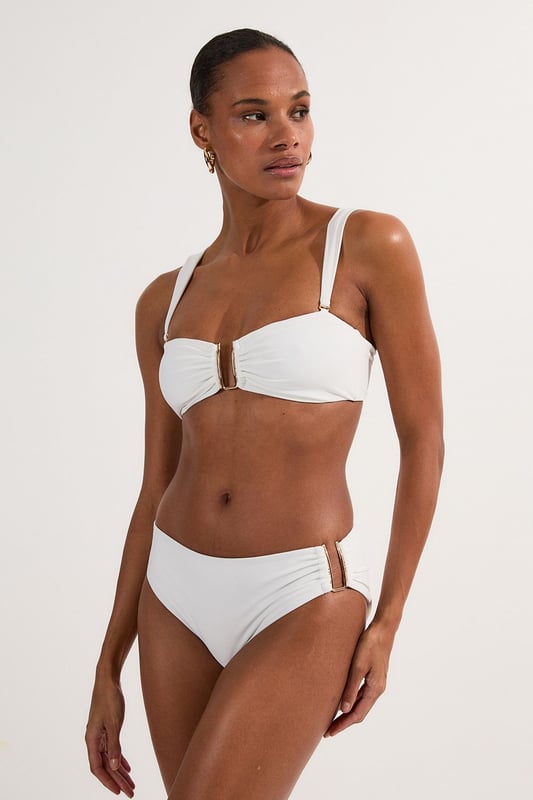 These sophisticated Karen Millen bikini bottoms bring a touch of luxury to your beachwear collection. The striking gold trim adds a refined accent that catches the light beautifully as you lounge poolside or stroll along the shore. Pair with the coordinating bandeau top for a cohesive look that's perfect for your summer getaway. Style with oversized sunglasses and a flowing kaftan for elegant poolside glamour, or team with a linen shirt and sandals when heading to a beachside lunch. These bottoms offer the perfect balance of comfort and sophistication for your next sun-soaked holiday.   Distinctive gold-tone trim detail on the side Mid-rise design offering comfortable coverage and a flattering silhouette Soft, stretchy fabric Sleek, minimalist design that pairs beautifully with the matching bandeau top  Matching piece sold separately.
