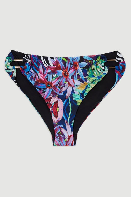 Make a statement this summer with these eye-catching tropical floral bikini bottoms from Karen Millen. The vivid print captures the essence of an exotic paradise, perfect for those sun-soaked days by the sea or poolside lounging. Pair with the matching top for a coordinated look, or mix and match with a solid-coloured piece for a personalised style. These versatile bottoms are ideal for a range of summer activities, from lazy beach days to active water sports. The stretchy fabric ensures comfort and a flattering fit, allowing you to move with confidence whether you're taking a dip or strolling along the shore. Embrace the tropical vibes and make these bikini bottoms your go-to choice for any sunny getaway or local beach day.  Vibrant tropical floral print for a bold beach look Stylish side strap detailing adds a touch of allure Mid-rise fit for comfortable coverage Stretchy fabric ensures a perfect fit and ease of movement Coordinating bikini top available for a complete set   Matching piece sold separately.