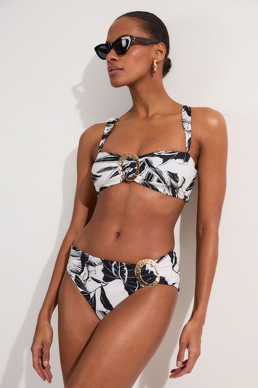 Make a statement this summer with these eye-catching high-waisted bikini bottoms from Karen Millen. The striking palm print design brings a touch of exotic flair to your beach ensemble, whilst the high-waisted cut elongates your legs and accentuates your curves. The gold-toned buckle detail adds a luxurious touch, perfect for those who love a bit of glamour by the pool. Pair with the matching top for a coordinated look, or mix and match with a solid-coloured bandeau for versatility. These bottoms are ideal for sunbathing, beach volleyball, or sipping cocktails at the resort bar. Whether you're jetting off to a tropical paradise or enjoying a staycation, these bikini bottoms will ensure you look and feel fabulous.  High-waisted design for a flattering silhouette Bold palm print pattern for a tropical vibe Decorative gold-toned buckle detail on the side Wide waistband for added comfort and support Moderate coverage at the back for confidence   Matching piece sold separately.