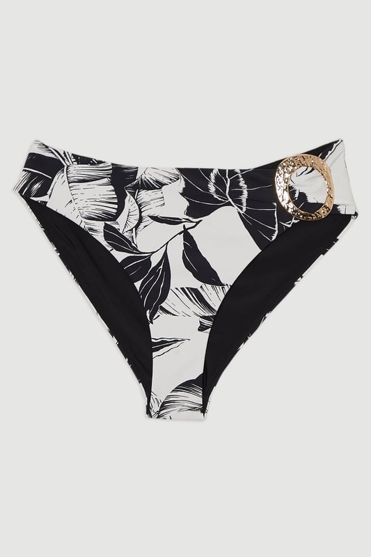 Make a statement this summer with these eye-catching high-waisted bikini bottoms from Karen Millen. The striking palm print design brings a touch of exotic flair to your beach ensemble, whilst the high-waisted cut elongates your legs and accentuates your curves. The gold-toned buckle detail adds a luxurious touch, perfect for those who love a bit of glamour by the pool. Pair with the matching top for a coordinated look, or mix and match with a solid-coloured bandeau for versatility. These bottoms are ideal for sunbathing, beach volleyball, or sipping cocktails at the resort bar. Whether you're jetting off to a tropical paradise or enjoying a staycation, these bikini bottoms will ensure you look and feel fabulous.  High-waisted design for a flattering silhouette Bold palm print pattern for a tropical vibe Decorative gold-toned buckle detail on the side Wide waistband for added comfort and support Moderate coverage at the back for confidence   Matching piece sold separately.