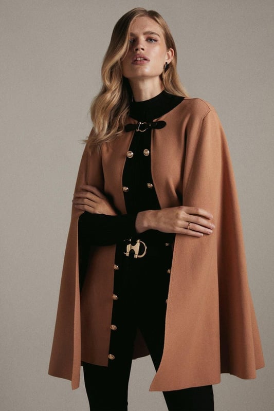 Nothing spells the changing of the seasons like a sleek cape. This covetable design is perfect for all your autumnal adventures, featuring an equestrian-style buckle fastening and cosy, knitted construction. Glossy military-inspired buttons line the front, adding to its luxe allure ? simply slip it on over your outfit for an instantly polished finish. Style: CapeDesign: PlainFabric: KnittedLength: RegularNeckline: CollarlessSleeve Length: Sleeveless Discover our blog post on the most popular coats & jackets for AW24 here.