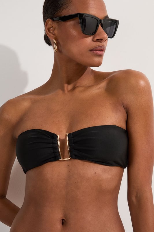 This Karen Millen bikini top combines contemporary design with practical versatility. The standout gold-tone hardware creates a luxurious focal point whilst the detachable straps offer two distinct looks - wear as a classic bandeau for minimal tan lines or attach the straps for additional support during active beach days. The gathered fabric detail adds a touch of sophistication that distinguishes this piece from ordinary swimwear. Perfect for making a statement whilst lounging poolside at exclusive resorts or during sun-soaked coastal holidays. Style with oversized sunglasses and delicate gold jewellery for a coordinated look, or layer under a sheer kaftan for elegant transitions from beach to bar. This bikini top effortlessly balances fashion-forward design with functional beachwear, ensuring you remain stylish whatever your holiday activities.   Elegant bandeau-style bikini top featuring a gold-tone metal trim at the front Versatile detachable straps allow for multiple styling options Soft gathered fabric detail Secure fit with comfortable stretch fabric Coordinating bottoms available to complete this refined beach ensemble  Matching piece sold separately.