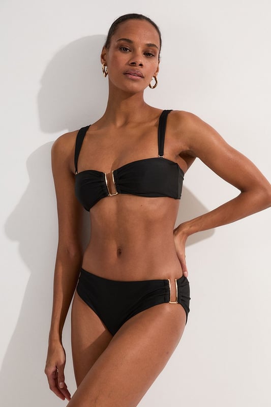 This Karen Millen bikini top combines contemporary design with practical versatility. The standout gold-tone hardware creates a luxurious focal point whilst the detachable straps offer two distinct looks - wear as a classic bandeau for minimal tan lines or attach the straps for additional support during active beach days. The gathered fabric detail adds a touch of sophistication that distinguishes this piece from ordinary swimwear. Perfect for making a statement whilst lounging poolside at exclusive resorts or during sun-soaked coastal holidays. Style with oversized sunglasses and delicate gold jewellery for a coordinated look, or layer under a sheer kaftan for elegant transitions from beach to bar. This bikini top effortlessly balances fashion-forward design with functional beachwear, ensuring you remain stylish whatever your holiday activities.   Elegant bandeau-style bikini top featuring a gold-tone metal trim at the front Versatile detachable straps allow for multiple styling options Soft gathered fabric detail Secure fit with comfortable stretch fabric Coordinating bottoms available to complete this refined beach ensemble  Matching piece sold separately.