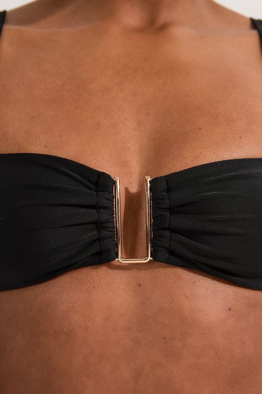 This Karen Millen bikini top combines contemporary design with practical versatility. The standout gold-tone hardware creates a luxurious focal point whilst the detachable straps offer two distinct looks - wear as a classic bandeau for minimal tan lines or attach the straps for additional support during active beach days. The gathered fabric detail adds a touch of sophistication that distinguishes this piece from ordinary swimwear. Perfect for making a statement whilst lounging poolside at exclusive resorts or during sun-soaked coastal holidays. Style with oversized sunglasses and delicate gold jewellery for a coordinated look, or layer under a sheer kaftan for elegant transitions from beach to bar. This bikini top effortlessly balances fashion-forward design with functional beachwear, ensuring you remain stylish whatever your holiday activities.   Elegant bandeau-style bikini top featuring a gold-tone metal trim at the front Versatile detachable straps allow for multiple styling options Soft gathered fabric detail Secure fit with comfortable stretch fabric Coordinating bottoms available to complete this refined beach ensemble  Matching piece sold separately.