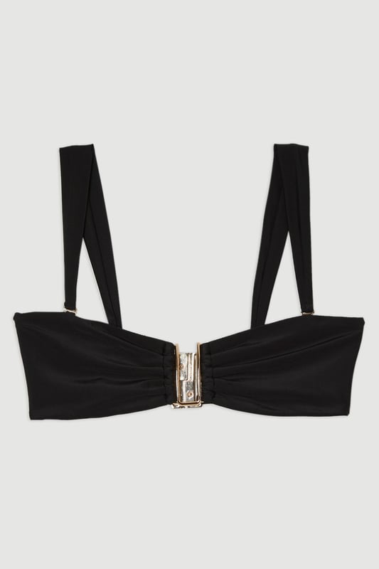 This Karen Millen bikini top combines contemporary design with practical versatility. The standout gold-tone hardware creates a luxurious focal point whilst the detachable straps offer two distinct looks - wear as a classic bandeau for minimal tan lines or attach the straps for additional support during active beach days. The gathered fabric detail adds a touch of sophistication that distinguishes this piece from ordinary swimwear. Perfect for making a statement whilst lounging poolside at exclusive resorts or during sun-soaked coastal holidays. Style with oversized sunglasses and delicate gold jewellery for a coordinated look, or layer under a sheer kaftan for elegant transitions from beach to bar. This bikini top effortlessly balances fashion-forward design with functional beachwear, ensuring you remain stylish whatever your holiday activities.   Elegant bandeau-style bikini top featuring a gold-tone metal trim at the front Versatile detachable straps allow for multiple styling options Soft gathered fabric detail Secure fit with comfortable stretch fabric Coordinating bottoms available to complete this refined beach ensemble  Matching piece sold separately.