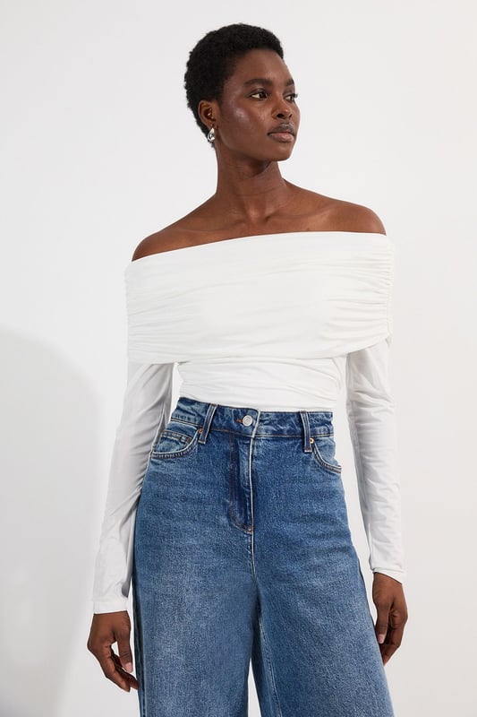 This Karen Millen Bardot bodysuit offers effortless sophistication for your everyday wardrobe. The off-shoulder design creates a flattering silhouette while the slinky jersey fabric drapes across the dcolletage. Style with high-waisted wide-leg jeans, or pair with a flowing midi skirt and ballet flats. For cooler evenings, layer with an oversized cardigan without compromising on the elegant neckline. The versatile design transitions seamlessly from daytime casual to evening drinks, simply swap to block heels and add statement earrings to transform your look.   Elegant Bardot neckline with a ruched fold-over detail Crafted from soft, drapey slinky jersey Secure bodysuit design Long sleeves