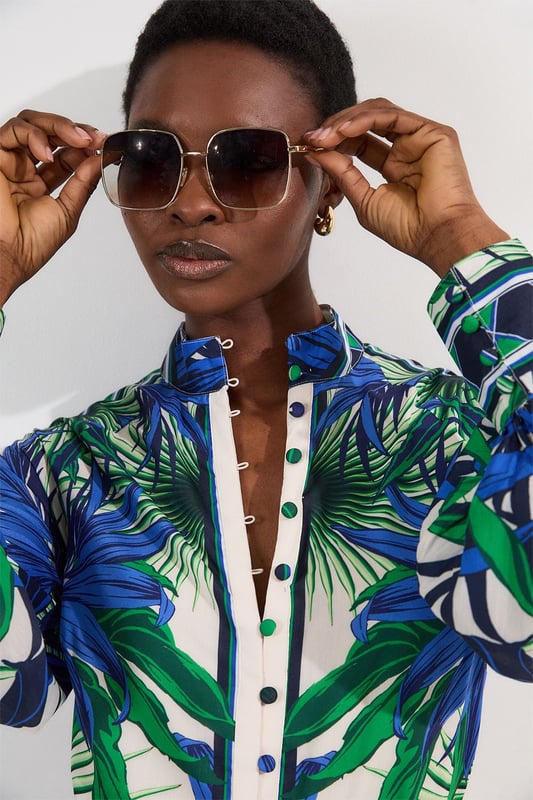 This eye-catching Karen Millen blouse showcases a vibrant mirrored floral pattern that demands attention. The lightweight voile fabric creates a fluid drape that moves with you, while the classic collared neckline adds structure to the relaxed silhouette. Style it with crisp white shorts and a slim belt for casual daytime gatherings, or tuck it into tailored trousers for a more polished look. The distinctive geometric border detailing on the cuffs provides a contemporary finishing touch that reflects Karen Millen's attention to detail.   Lightweight voile fabric with mirrored floral print throughout collared neckline with button-down front detail Geometric border detailing on cuffs Relaxed silhouette with full-length sleeves