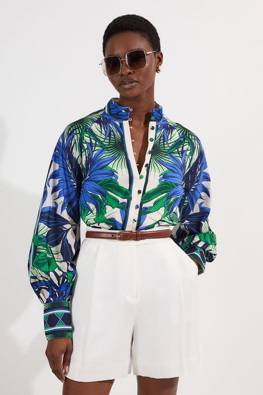 This eye-catching Karen Millen blouse showcases a vibrant mirrored floral pattern that demands attention. The lightweight voile fabric creates a fluid drape that moves with you, while the classic collared neckline adds structure to the relaxed silhouette. Style it with crisp white shorts and a slim belt for casual daytime gatherings, or tuck it into tailored trousers for a more polished look. The distinctive geometric border detailing on the cuffs provides a contemporary finishing touch that reflects Karen Millen's attention to detail.   Lightweight voile fabric with mirrored floral print throughout collared neckline with button-down front detail Geometric border detailing on cuffs Relaxed silhouette with full-length sleeves