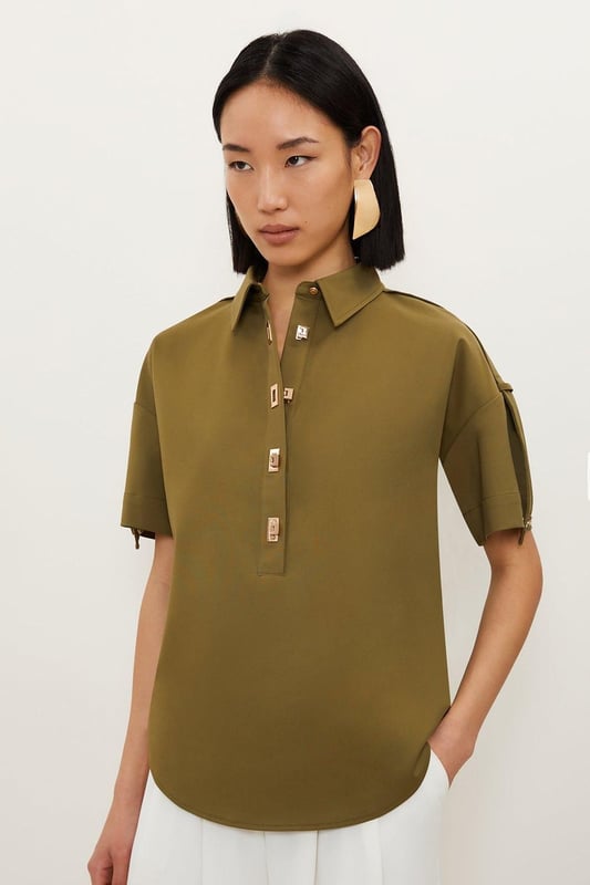 Feel formal in our shirt, with high quality cotton fabric, as well as a straight fit and short sleeves, and metallic clasp detailing down the front. Style it with anything from tailored trousers to denim jeans for looks perfect for anything from office days to dinner dates. Techno Cotton Woven Short Sleeve Hardwear Detail Shirt High Quality, Soft Cotton Fabric Flattering Straight Fit Formal Collar Accent Casual Short Sleeves Gold Clasp DetailingBrowse this seasons women's work tops or discover the full range of workwear now.Matching piece sold separately.