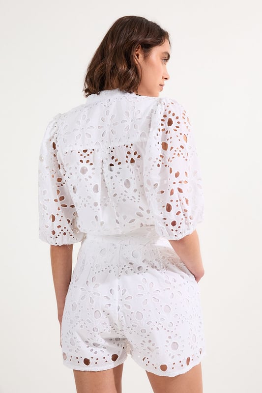 These exquisite broderie shorts from Karen Millen showcase exceptional craftsmanship with their intricate cut-out pattern. The high-waisted design creates a flattering shape that pairs with the woven shirt. For casual daywear, team with a simple tucked-in blouse and trainers for brunch with friends, or dress up with a fitted bodysuit and leather sandals for summer garden parties. The versatile length makes these shorts perfect for warm-weather holidays, simply add oversized sunglasses and a straw tote for effortless sophistication. The cotton fabric ensures breathability whilst the structured silhouette maintains shape throughout the day, making these shorts an essential addition to your warm-weather wardrobe for family gatherings and casual outings alike.  Intricate broderie anglaise detailing creates a floral pattern throughout High-waisted design with pleated front Scalloped hem with delicate cut-out pattern Side pockets