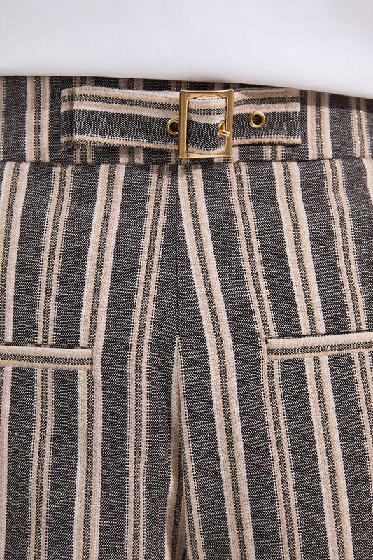 These Karen Millen tailored city shorts combine sophistication with casual comfort for effortless daywear styling. The distinctive stripe pattern with subtle sparkle threads creates visual interest while maintaining versatility. Style them with a crisp white t-shirt and an oversized blazer for a polished weekend brunch look, or pair with a lightweight knit and trainers for shopping trips and casual gatherings. The structured silhouette and linen blend fabric make these shorts perfect for warm-weather socialising without compromising on style. For a coordinated summer ensemble, match with flat sandals and a crossbody bag, adding sunglasses for a touch of chic practicality. These shorts transition seamlessly from daytime family gatherings to early evening garden parties, offering both comfort and refined style.  Tailored city shorts featuring a distinctive sparkle stripe pattern for a touch of subtle glamour Crafted with linen blend fabric for breathable comfort during warm weather Elegant gold-tone buckle detail at the waistband adds a refined finishing touch Practical side pockets for convenient storage of small essentials Versatile 45cm length offering a flattering fit that pairs beautifully with various tops  Matching piece available, sold separately.