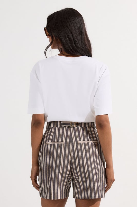These Karen Millen tailored city shorts combine sophistication with casual comfort for effortless daywear styling. The distinctive stripe pattern with subtle sparkle threads creates visual interest while maintaining versatility. Style them with a crisp white t-shirt and an oversized blazer for a polished weekend brunch look, or pair with a lightweight knit and trainers for shopping trips and casual gatherings. The structured silhouette and linen blend fabric make these shorts perfect for warm-weather socialising without compromising on style. For a coordinated summer ensemble, match with flat sandals and a crossbody bag, adding sunglasses for a touch of chic practicality. These shorts transition seamlessly from daytime family gatherings to early evening garden parties, offering both comfort and refined style.  Tailored city shorts featuring a distinctive sparkle stripe pattern for a touch of subtle glamour Crafted with linen blend fabric for breathable comfort during warm weather Elegant gold-tone buckle detail at the waistband adds a refined finishing touch Practical side pockets for convenient storage of small essentials Versatile 45cm length offering a flattering fit that pairs beautifully with various tops  Matching piece available, sold separately.