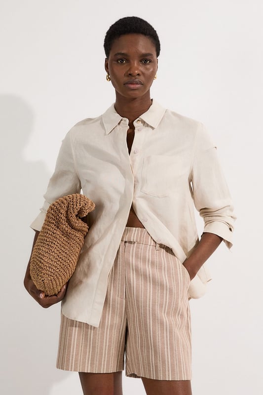 These Karen Millen tailored city shorts combine sophistication with casual comfort for effortless daywear styling. The distinctive stripe pattern with subtle sparkle threads creates visual interest while maintaining versatility. Style them with a crisp white t-shirt and an oversized blazer for a polished weekend brunch look, or pair with a lightweight knit and trainers for shopping trips and casual gatherings. The structured silhouette and linen blend fabric make these shorts perfect for warm-weather socialising without compromising on style. For a coordinated summer ensemble, match with flat sandals and a crossbody bag, adding sunglasses for a touch of chic practicality. These shorts transition seamlessly from daytime family gatherings to early evening garden parties, offering both comfort and refined style.  Tailored city shorts featuring a distinctive sparkle stripe pattern for a touch of subtle glamour Crafted with linen blend fabric for breathable comfort during warm weather Elegant gold-tone buckle detail at the waistband adds a refined finishing touch Practical side pockets for convenient storage of small essentials Versatile 45cm length offering a flattering fit that pairs beautifully with various tops  Matching piece available, sold separately.