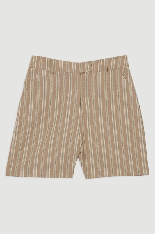 These Karen Millen tailored city shorts combine sophistication with casual comfort for effortless daywear styling. The distinctive stripe pattern with subtle sparkle threads creates visual interest while maintaining versatility. Style them with a crisp white t-shirt and an oversized blazer for a polished weekend brunch look, or pair with a lightweight knit and trainers for shopping trips and casual gatherings. The structured silhouette and linen blend fabric make these shorts perfect for warm-weather socialising without compromising on style. For a coordinated summer ensemble, match with flat sandals and a crossbody bag, adding sunglasses for a touch of chic practicality. These shorts transition seamlessly from daytime family gatherings to early evening garden parties, offering both comfort and refined style.  Tailored city shorts featuring a distinctive sparkle stripe pattern for a touch of subtle glamour Crafted with linen blend fabric for breathable comfort during warm weather Elegant gold-tone buckle detail at the waistband adds a refined finishing touch Practical side pockets for convenient storage of small essentials Versatile 45cm length offering a flattering fit that pairs beautifully with various tops  Matching piece available, sold separately.