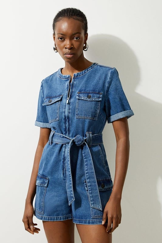 Elevate your summer wardrobe in our playsuit, with high quality denim fabric, featuring a belted waistline, as well as a utility design and relaxed fit shorts. Styles well with trainers or sandals for a summer outfit that can be worn again and again. Denim Cargo Pocket Belted Playsuit High Quality Denim Fabric Flattering Relaxed Fit Summery Short Sleeves Unique Cargo Style Zip Front Fastenings Belted Waist for a Cinched Silhouette
